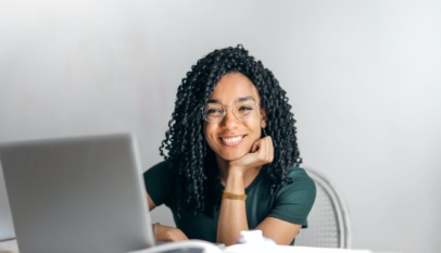 Photo by Andrea Piacquadio, happy ethnic woman sitting at table with laptop